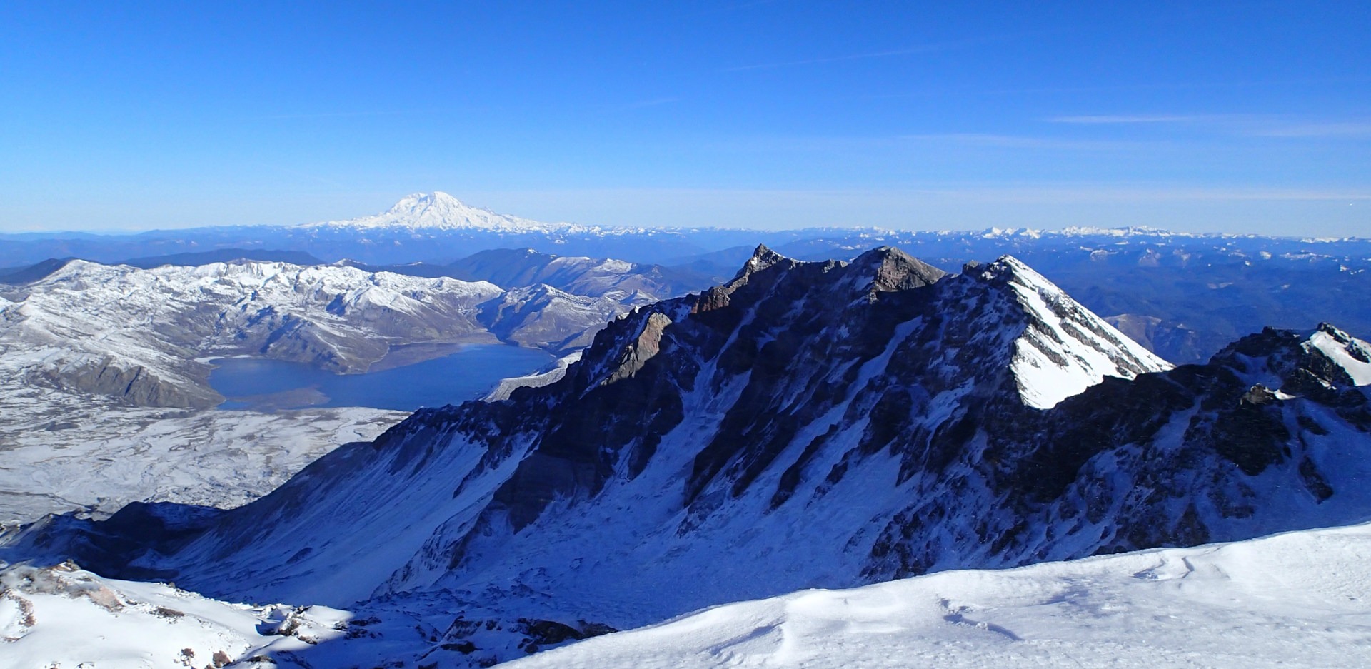 Crater rim with Spirit Lake and Mount Rainier in the background.