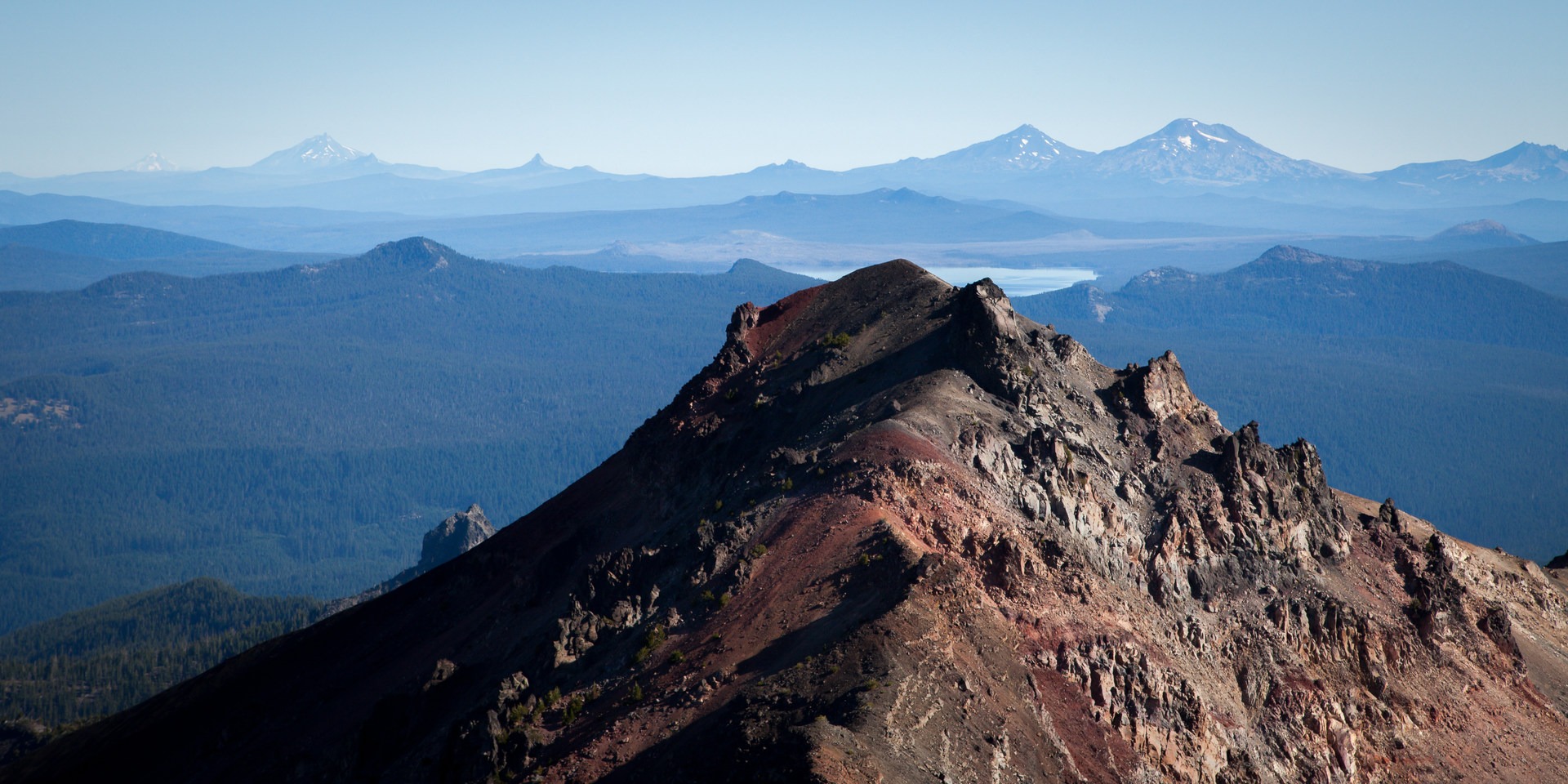 Foreground, bottom: Mount Yoran (7,100 ft). Waldo Lake is north. Peaks, right to left: Broken Top (9,177 ft), South and Middle Sisters (10,358 ft), Mount Washington (7,795 ft), Three Fingered Jack (7,844 ft), Mount Jefferson (10,495 ft), and Mount Hood (1