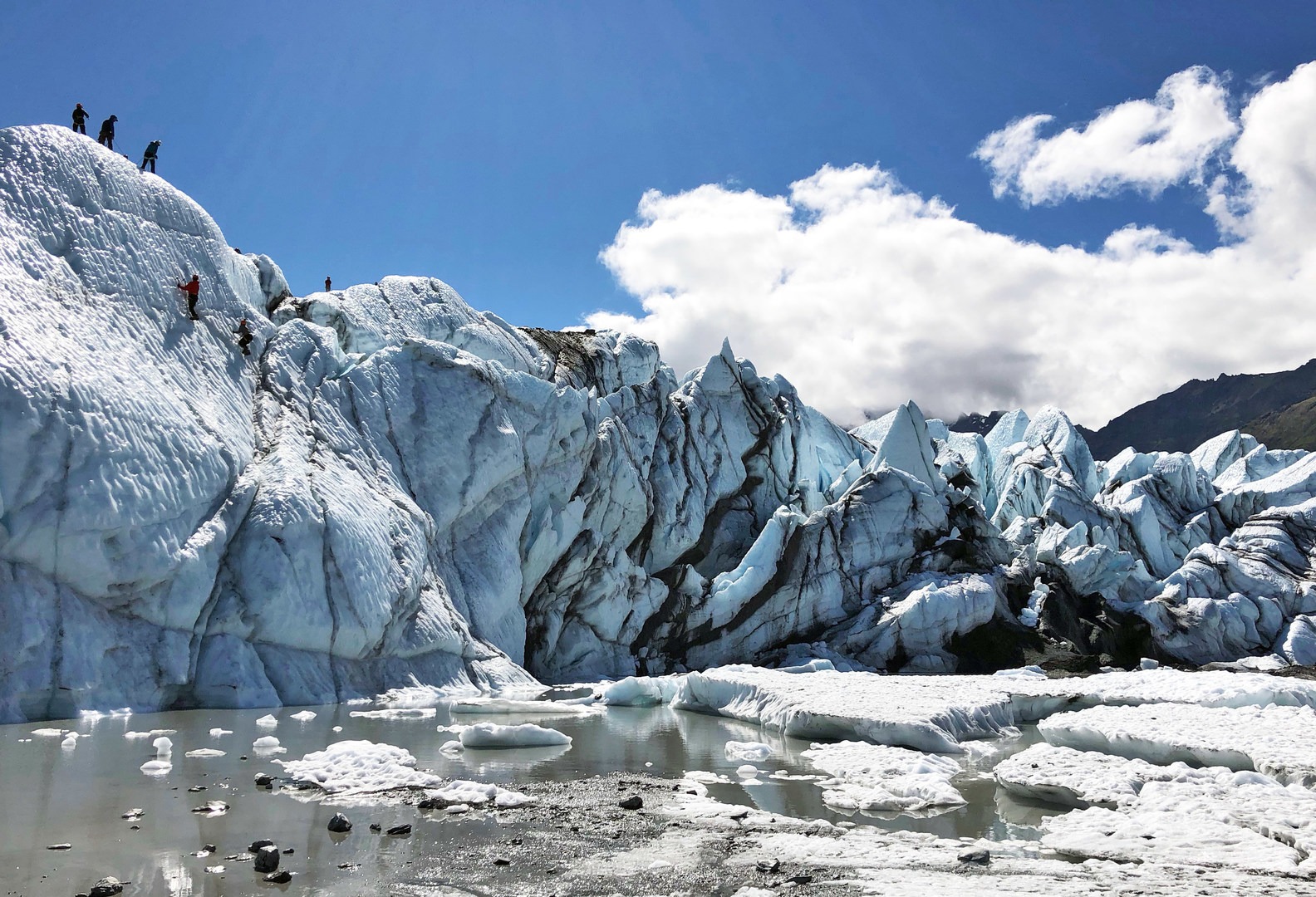 The main headwall of the Matanuska on blue bird summer day. Notice the tiny ice climbers rappelling down and climbing back up the face.
