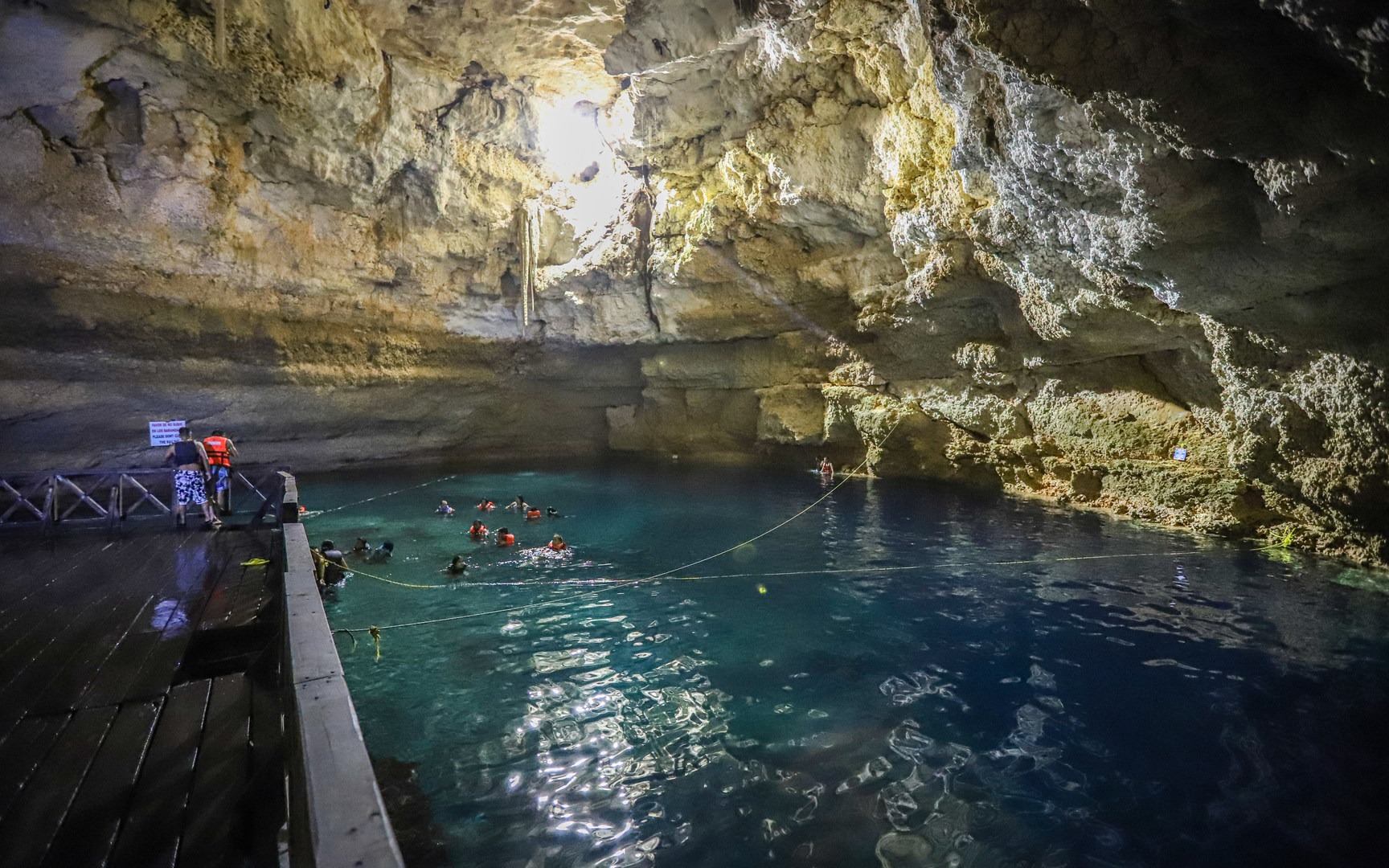The cenote's waters are clear and blue.