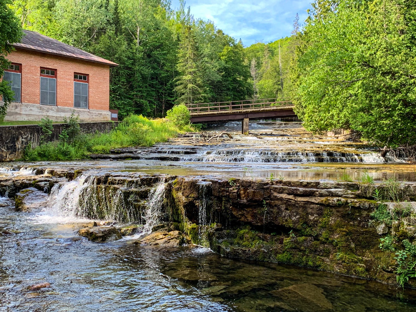 Near the bottom of the falls looking up and South toward one of the hydro plant out buildings as well as the bridge for access.