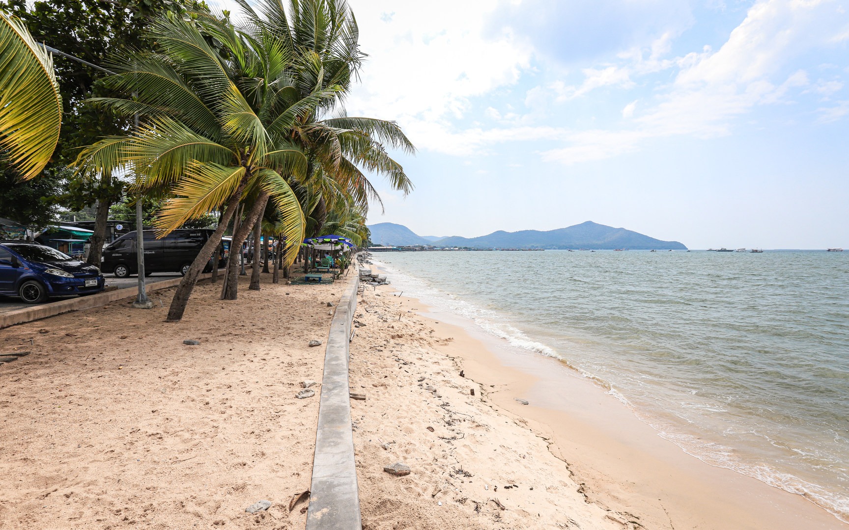 The beach has a short sandy area adjacent to a retaining wall beside the sea.