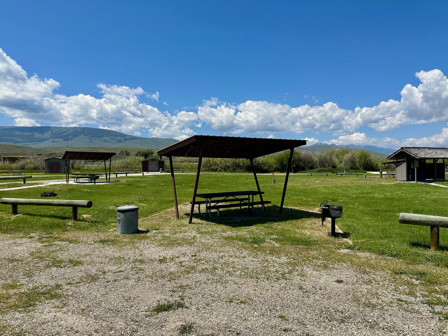 Picnic tables are covered with a shade structure.