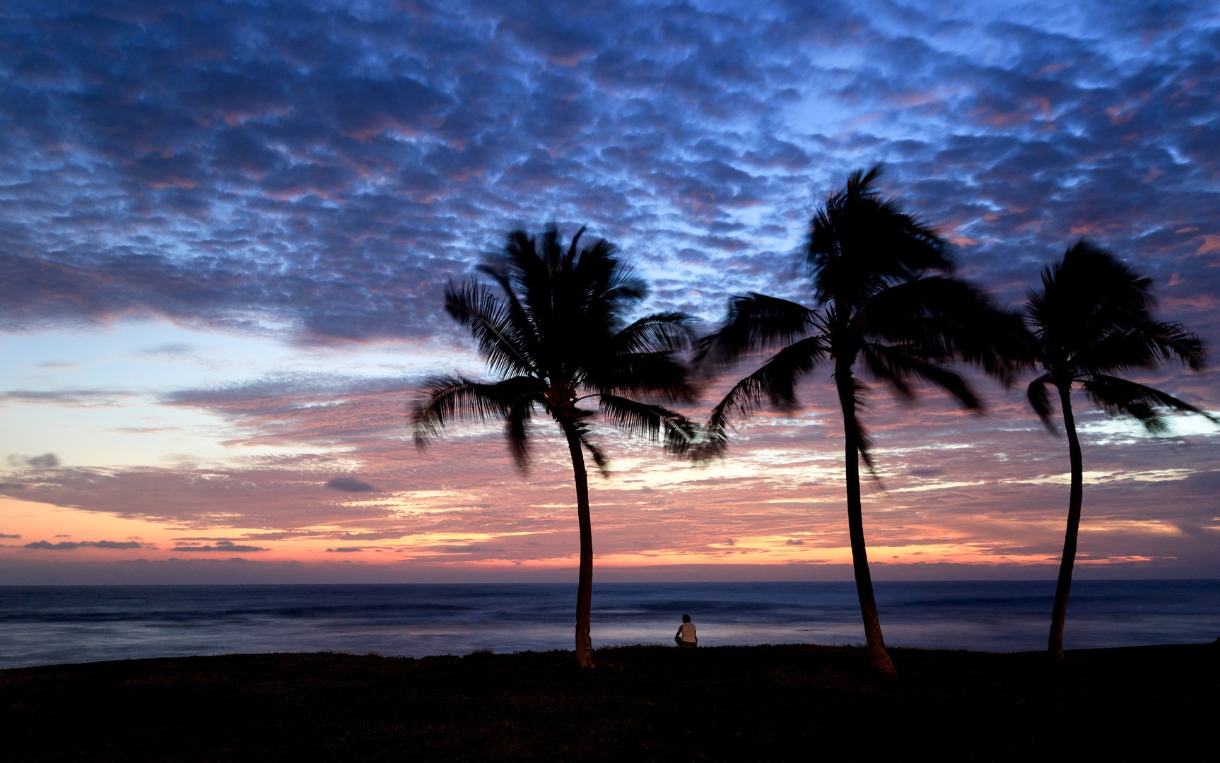 A beach goer enjoys twilight under the palms at Ma'ili Point.