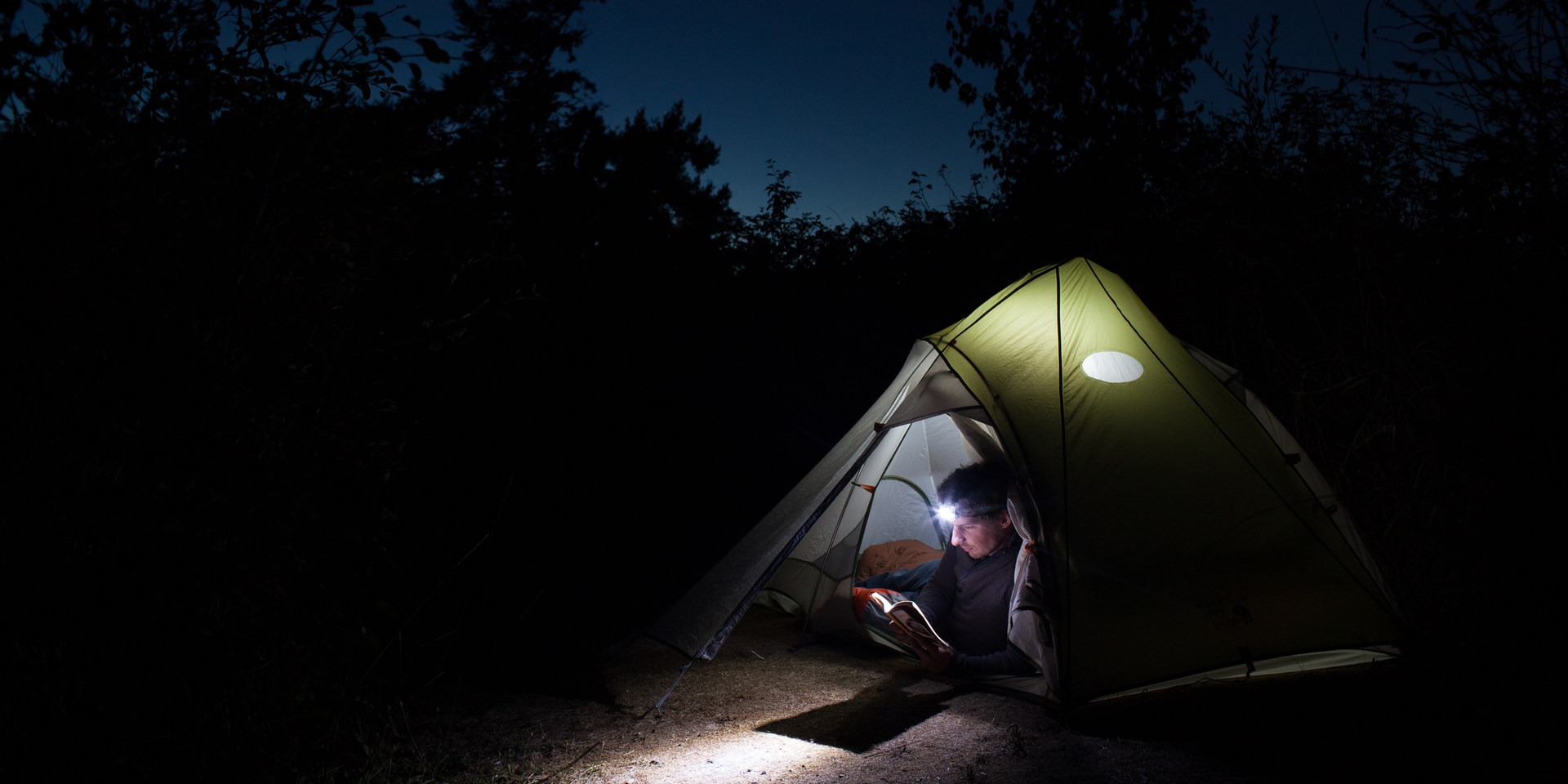A camper reads in his tent as the light fades on Clark Island.
