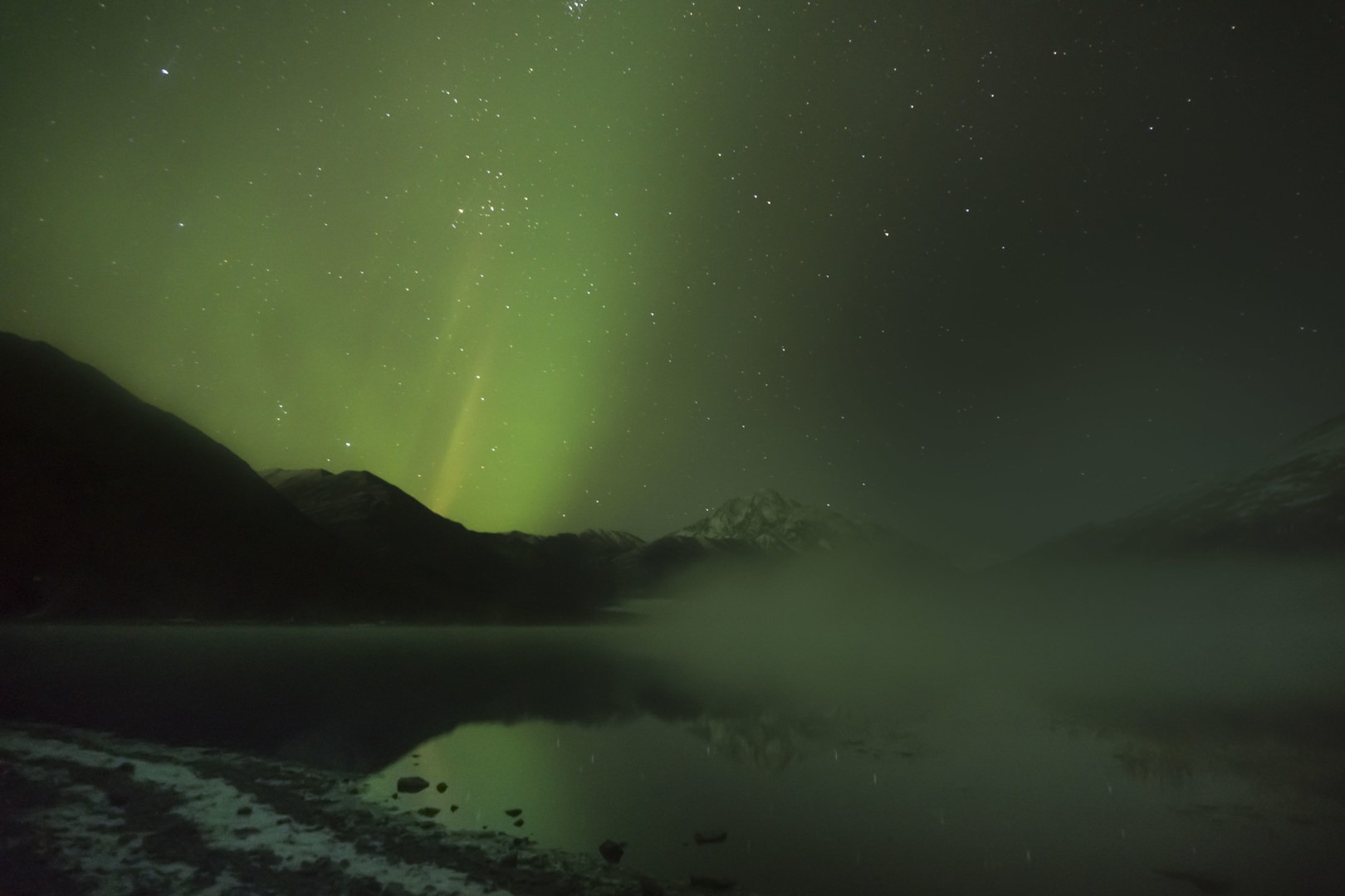 A misty Alaskan mountain over Eklutna Lake playing with the Aurora Borealis